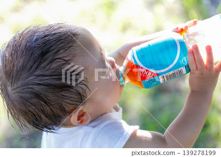 特寫鏡頭拍攝一個幼兒的後腦勺，他正迅速地喝著飲料。 139278199