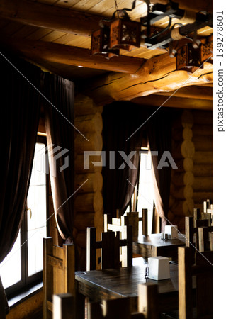 Empty rustic restaurant interior with wooden tables and chairs, illuminated by bright window light Empty rustic restaurant interior with wooden tables and chairs, illuminated by bright window light 139278601