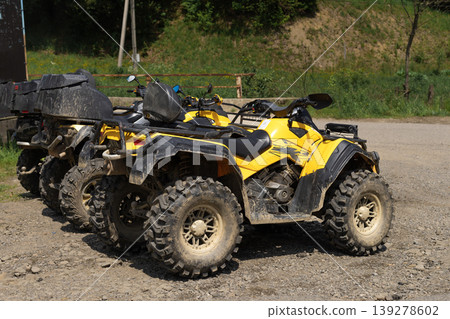 Line of powerful yellow quad bikes parked on a sunny dirt trail ready for adventure 139278602