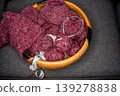 Soft burgundy yarn balls with knitting needles in basket 139278838