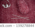 Soft burgundy yarn balls with knitting needles 139278844