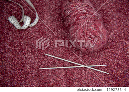 Soft burgundy yarn balls with knitting needles 139278844