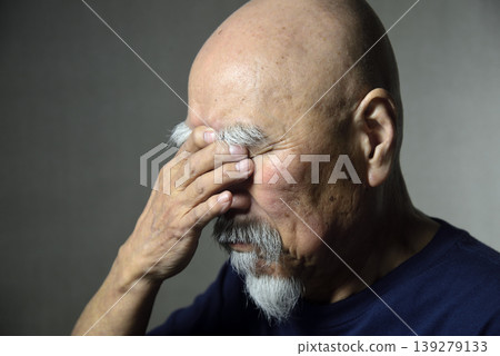 A bearded old man covering his face with his hands 139279133