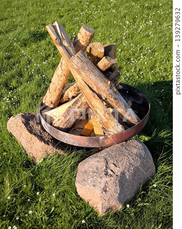 Prepared firewood in a metal bowl on a green lawn Prepared firewood in a metal bowl on a green lawn 139279632
