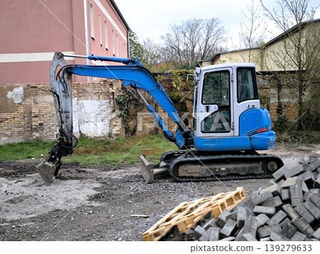Blue compact excavator with bucket at construction site Blue compact excavator with bucket at construction site 139279633