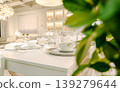 A modern dining table setting featuring white tableware and wine glasses. 139279644