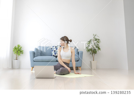 一位年輕女子在家中進行線上瑜珈直播。 一位年輕女子在家中進行線上瑜珈直播。 139280235