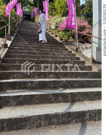 A person in a kimono climbing stone steps and the approach to a temple. A person in a kimono climbing stone steps and the approach to a temple. 139280239