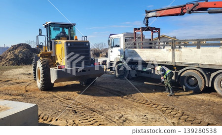 Heavy construction machinery and white trucks working at an industrial site, earthmoving equipment, urban engineering Heavy construction machinery and white trucks working at an industrial site, earthmoving equipment, urban engineering 139280538