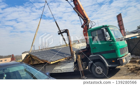 Green manipulator truck lifting building materials on a construction site, heavy machinery logistics, industrial project Green manipulator truck lifting building materials on a construction site, heavy machinery logistics, industrial project 139280566