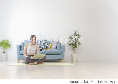 一位年輕女子在家做線上瑜珈。 一位年輕女子在家做線上瑜珈。 139280704