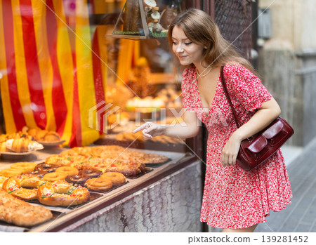 Girl choosing sweet cookies or cupcakes at street bakery display 139281452