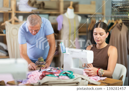 Girl master sew clothes in sewing machine, senior craftsman draw dress pattern Girl master sew clothes in sewing machine, senior craftsman draw dress pattern 139281457