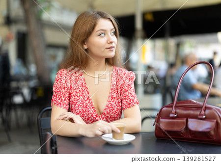 Pretty young woman relaxing and drinking coffee sitting on street cafe in day Pretty young woman relaxing and drinking coffee sitting on street cafe in day 139281527