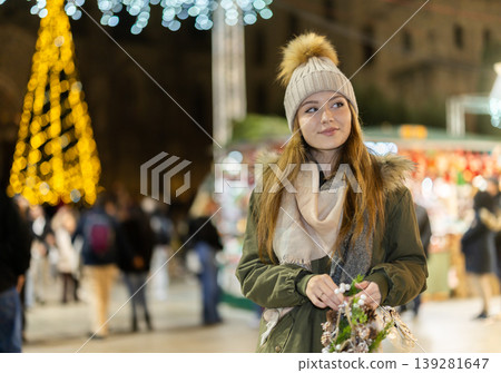 woman stands against the background of a Christmas tree on the street 139281647