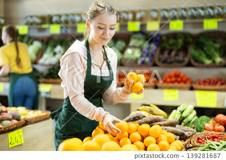 Girl employees in uniform holding mandarines in grocery shop 139281687