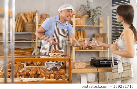 Elderly man seller gives box of pastries to woman buyer Elderly man seller gives box of pastries to woman buyer 139281715