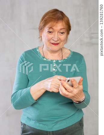 Positive interested aged woman looking at mobile phone 139281760