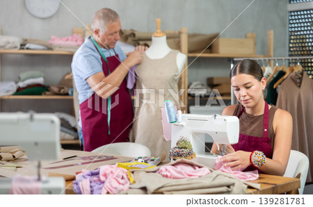Young woman sews on machine male assistant sews on mannequin Young woman sews on machine male assistant sews on mannequin 139281781
