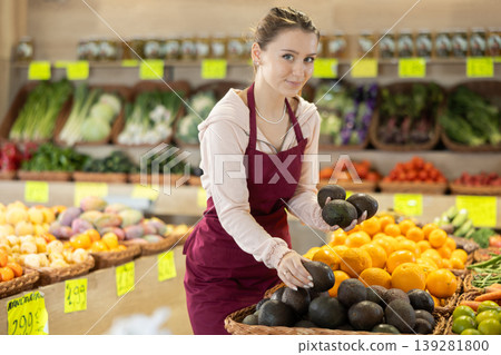 Female grocery store employee places fresh kiwis into crates on sales floor 139281800