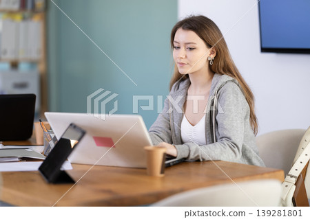 Young woman sitting at desk and working on laptop Young woman sitting at desk and working on laptop 139281801