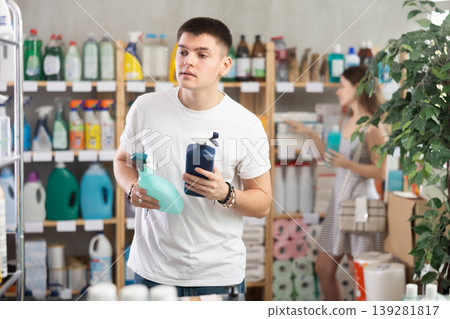 Man chooses sprays to clean the house in front of the buyer Man chooses sprays to clean the house in front of the buyer 139281817
