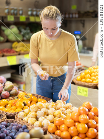 Young woman choosing a yellow plum in a store 139281821