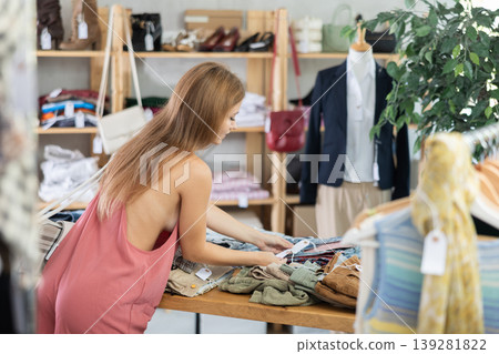 Young woman standing choosing pants in store Young woman standing choosing pants in store 139281822