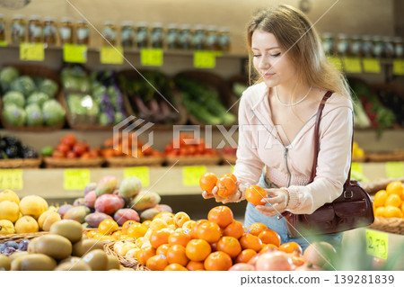 Young woman chooses tangerines in store Young woman chooses tangerines in store 139281839