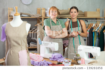 Female dressmakers standing in the workshop near the table Female dressmakers standing in the workshop near the table 139281858