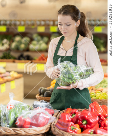 Woman employees in uniform holding fresh bell pepper in grocery shop 139281919
