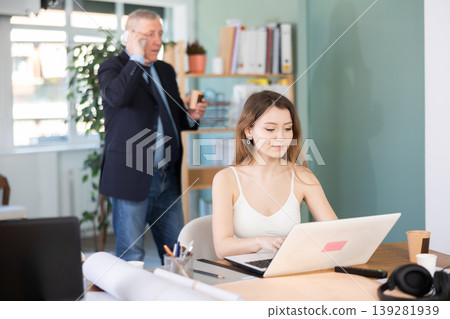 Young woman is typing on a laptop in front of her boss Young woman is typing on a laptop in front of her boss 139281939