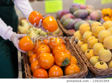 Hands of female seller puts persimmon on counter Hands of female seller puts persimmon on counter 139281944