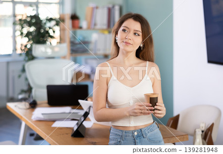 Woman holds a cup of strong coffee in the morning in the office Woman holds a cup of strong coffee in the morning in the office 139281948