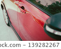 Close-up of dented red car door with side mirror and wheel visib 139282267