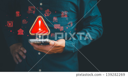 Cyber security warning on smartphone for data breach and online fraud prevention. Professional man holding phone with phishing security alert icon for financial crime protection. Cyber security warning on smartphone for data breach and online fraud prevention. Professional man holding phone with phishing security alert icon for financial crime protection. 139282269