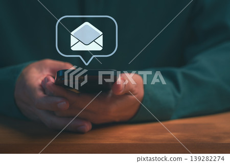 Close up of hands holding a smartphone with an email notification icon. Concept of digital communication, business message, email marketing, online inbox, and newsletter. Close up of hands holding a smartphone with an email notification icon. Concept of digital communication, business message, email marketing, online inbox, and newsletter. 139282274