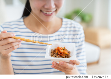 A young woman's hands as she eats kimchi and natto. A young woman's hands as she eats kimchi and natto. 139282513