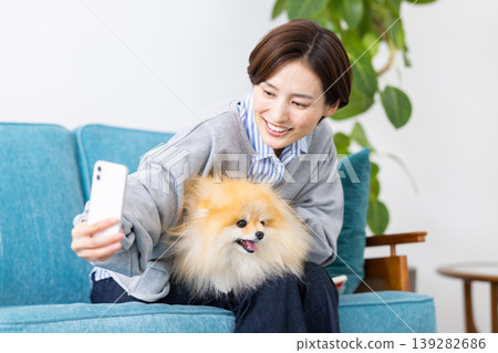 Lifestyle: A woman takes photos of her dog with her smartphone. 139282686