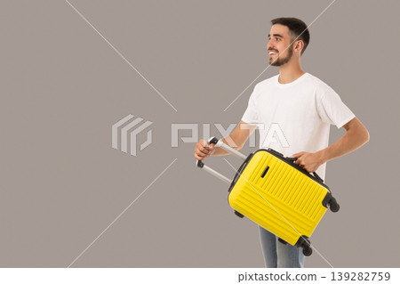 Young man enjoys traveling while holding a bright yellow suitcase Young man enjoys traveling while holding a bright yellow suitcase 139282759
