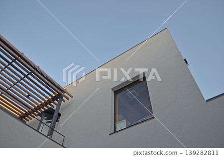 一幅簡單的構圖,由建築物的牆壁、天空和抬頭看向窗戶的視線組成。 一幅簡單的構圖,由建築物的牆壁、天空和抬頭看向窗戶的視線組成。 139282811