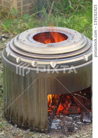 對用廢棄舊洗衣機改造的不銹鋼洗衣桶製成的戶外爐灶進行燃燒測試。 對用廢棄舊洗衣機改造的不銹鋼洗衣桶製成的戶外爐灶進行燃燒測試。 139282825