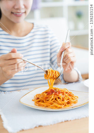 一位年輕女子午餐在吃義大利麵。 一位年輕女子午餐在吃義大利麵。 139283154