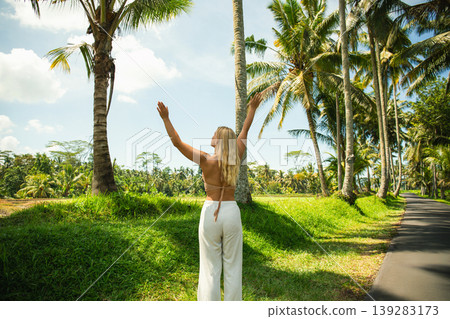 A woman embraces the tropical landscape surrounded by palm trees A woman embraces the tropical landscape surrounded by palm trees 139283173