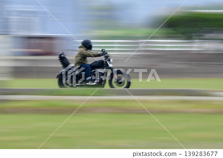 一輛黑色摩托車飛馳在鄉村景色中。 一輛黑色摩托車飛馳在鄉村景色中。 139283677