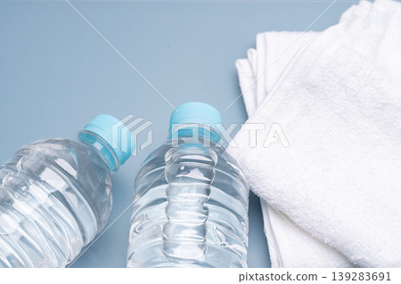 Product photography of a water bottle and a towel placed against a blue background. 139283691