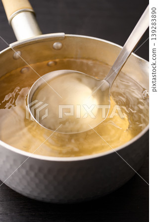 用湯匙舀起滾燙的高湯。 用湯匙舀起滾燙的高湯。 139283890