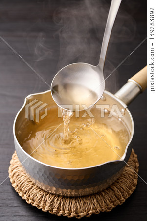 Scoop up the piping hot broth with a ladle. Scoop up the piping hot broth with a ladle. 139283892