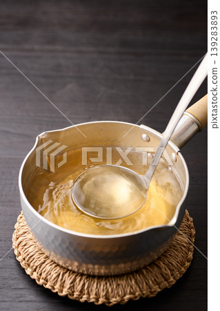 Scoop up the piping hot broth with a ladle. Scoop up the piping hot broth with a ladle. 139283893