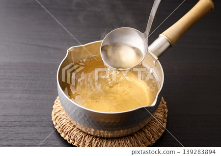 用湯匙舀起滾燙的高湯。 用湯匙舀起滾燙的高湯。 139283894